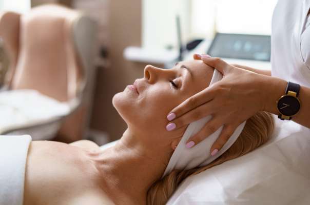 Face massage. Close-up of adult woman getting spa massage treatment at beauty spa salon. Spa skin and body care. Facial beauty treatment. Cosmetology.